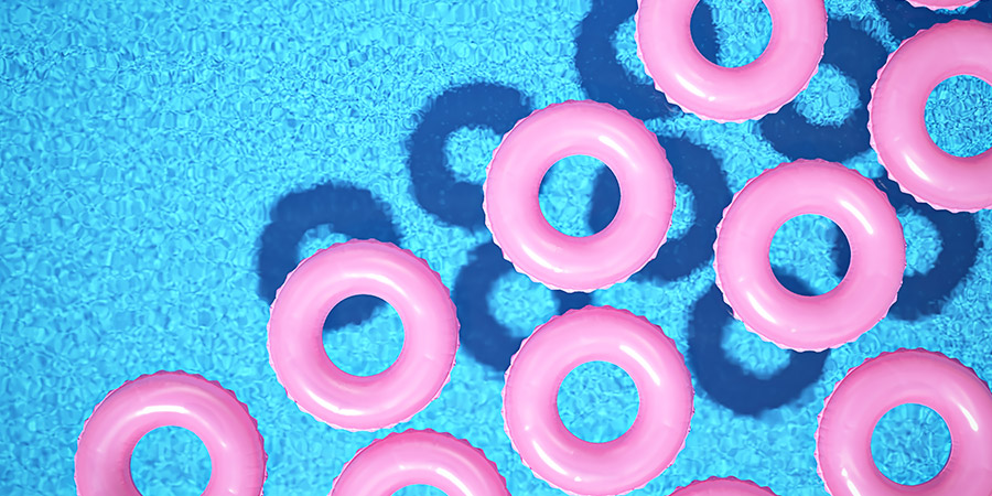 Circular pink pool floats in a sunlit pool.