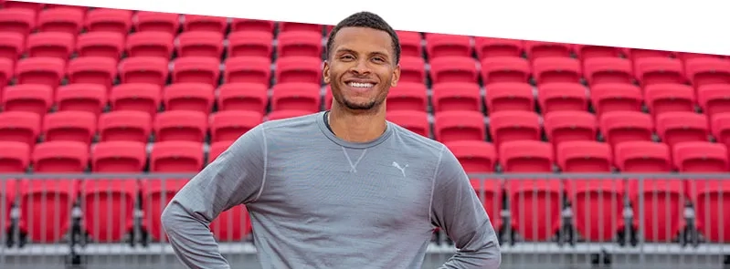 Andre De Grasse smiling in front of stands